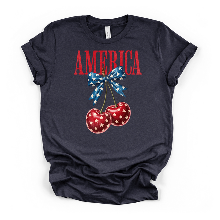 Heather navy t-shirt featuring a patriotic cherry illustration with white stars and a blue star-print bow with America text in red on the front