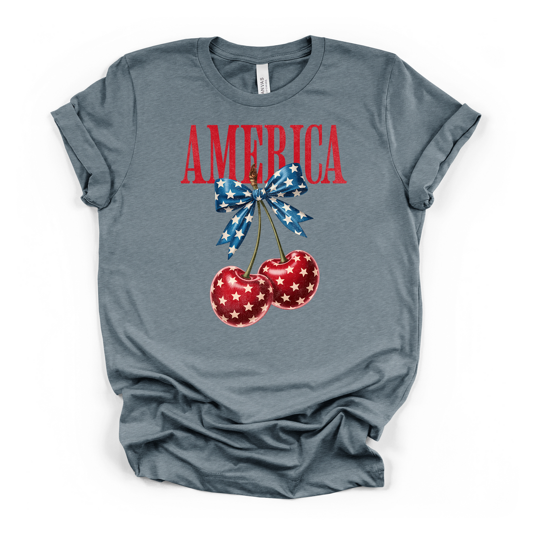 Heather slate t-shirt with a cute patriotic cherry and blue star bow graphic with America printed in distressed red lettering on the front