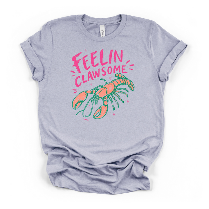 Heather blue t-shirt with a colorful illustrated lobster in coral and teal with sparkles and Feelin Clawsome printed in hot pink on the front