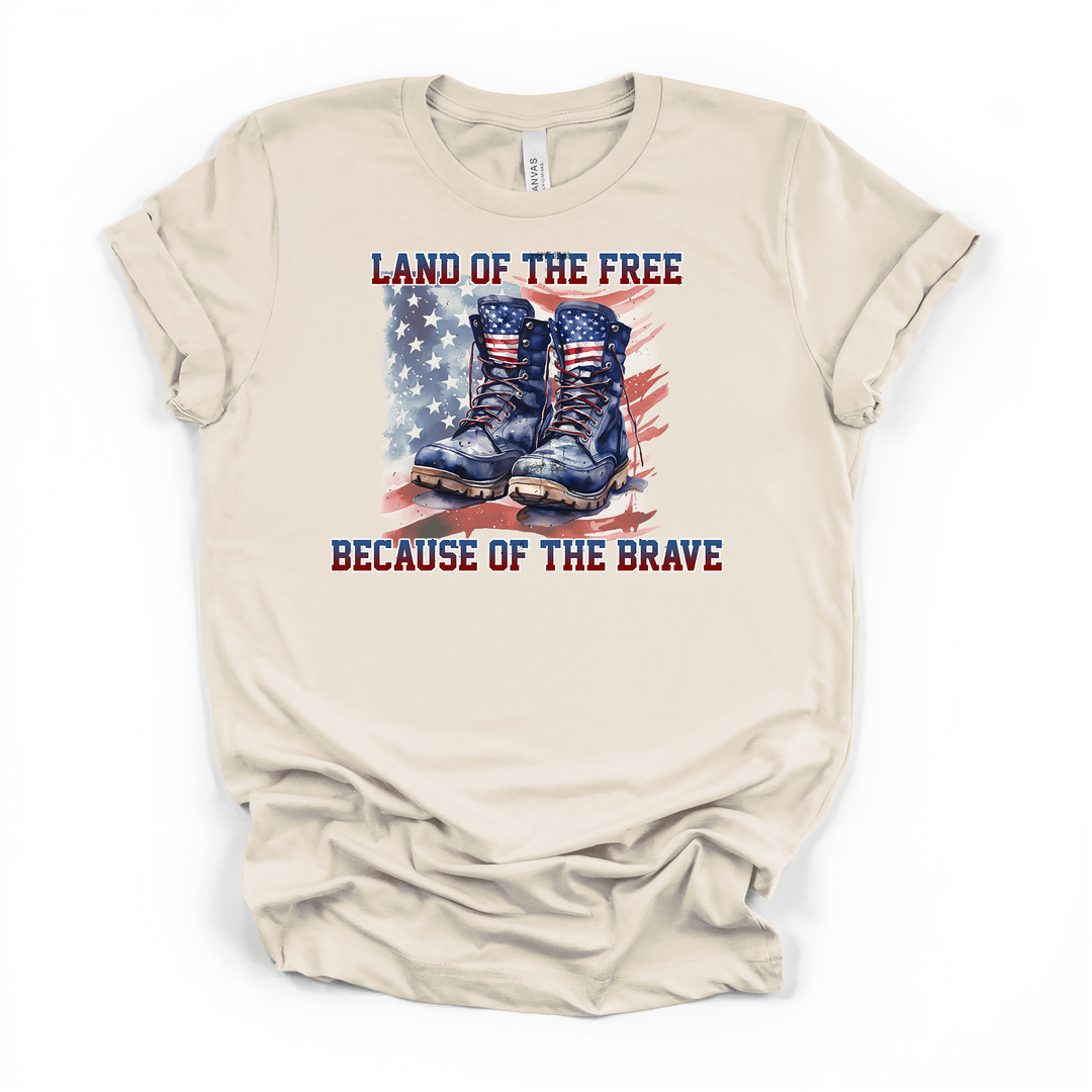 Natural cream t-shirt with a watercolor American flag and military combat boots graphic and Land of the Free Because of the Brave printed on the front