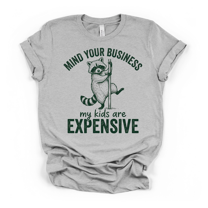 Athletic heather t-shirt with a funny raccoon pole graphic and Mind Your Business My Kids Are Expensive printed in dark green on the front