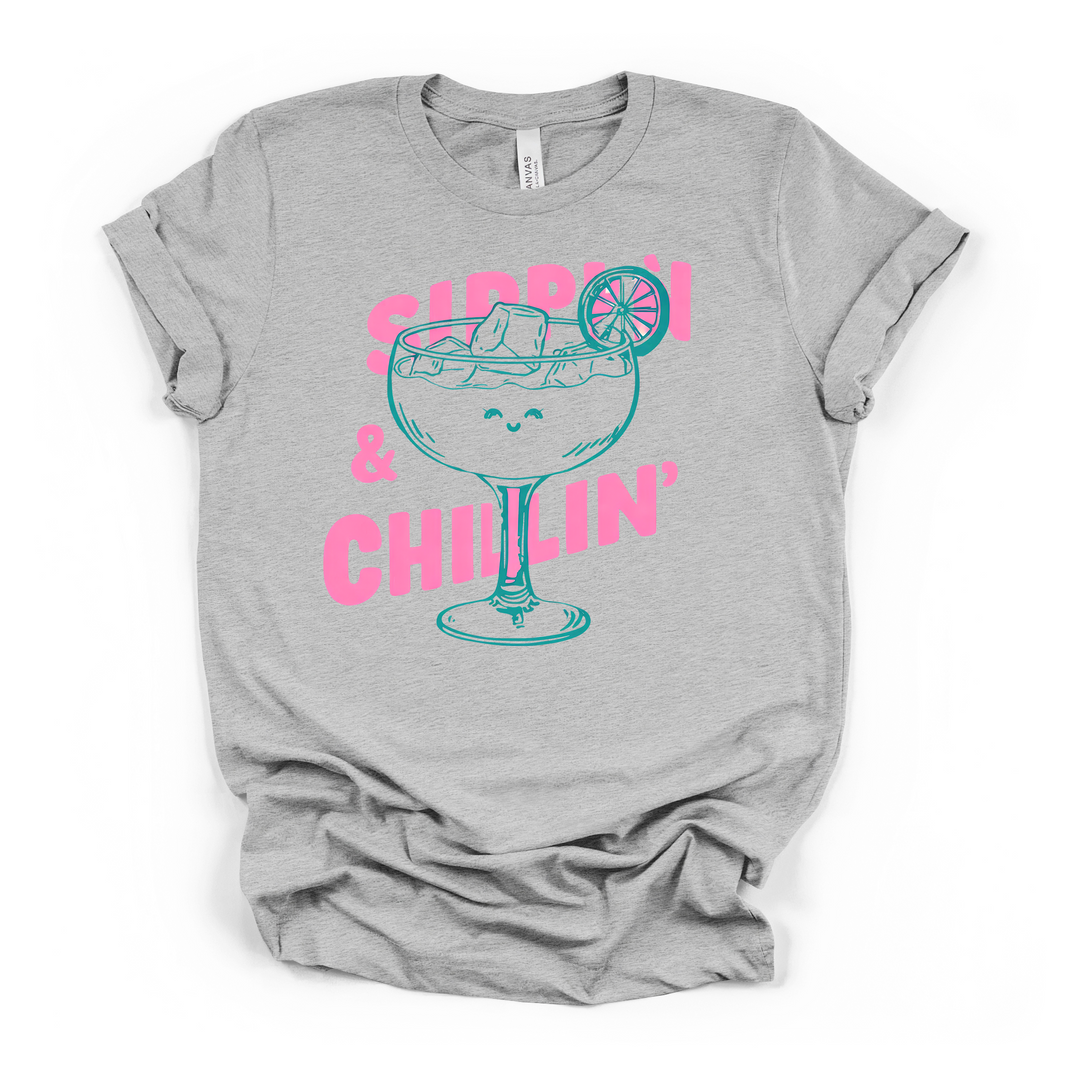 Sippin and Chillin cocktail graphic t-shirt in athletic heather with smiling margarita glass and bold pink lettering