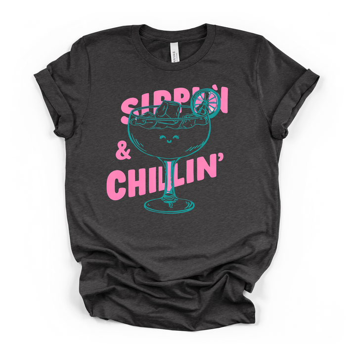 Sippin and Chillin cocktail graphic t-shirt in dark grey with smiling margarita glass and bold pink lettering