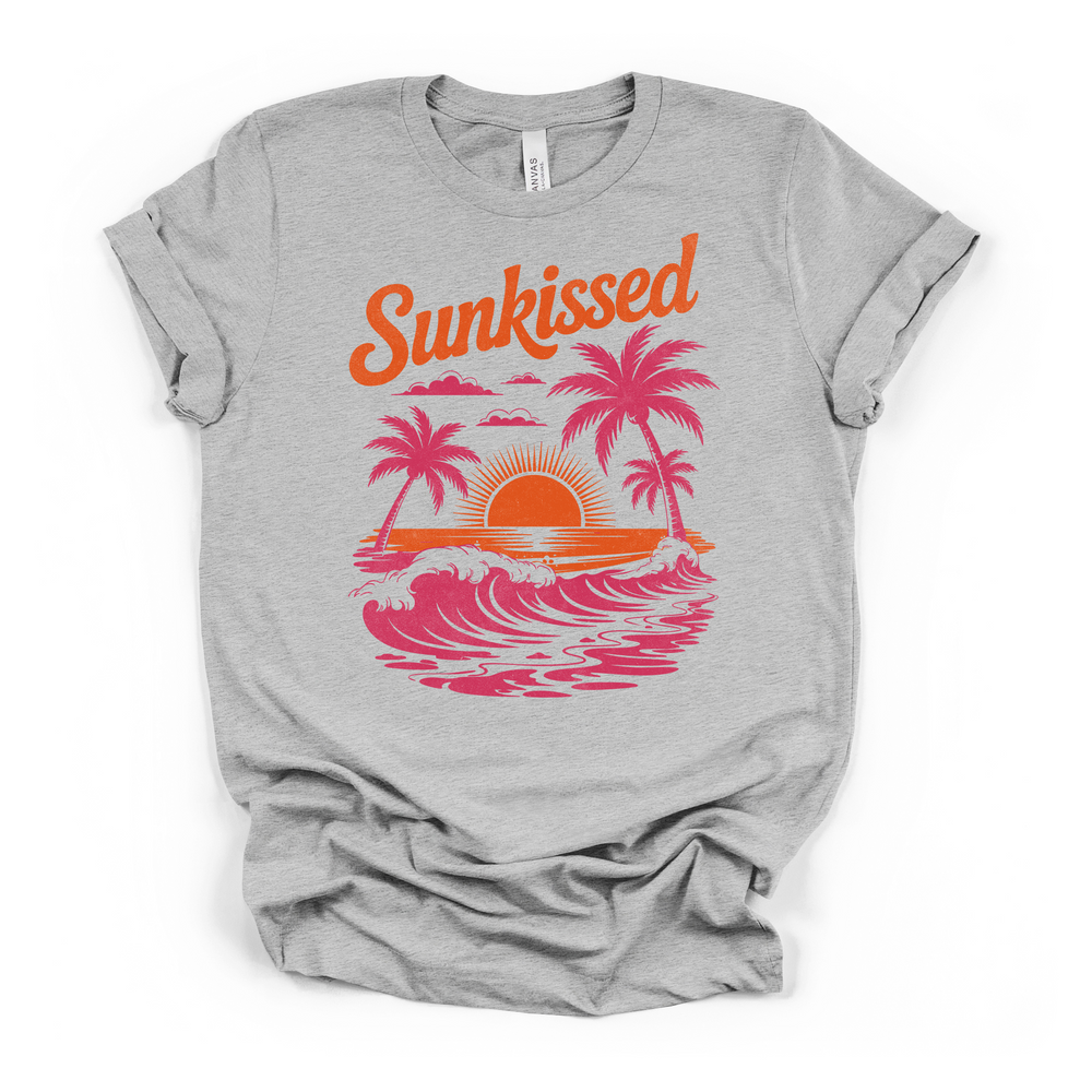 Athletic heather t-shirt featuring a retro Sunkissed beach scene with pink palm trees ocean waves and a glowing orange sunset graphic on the front