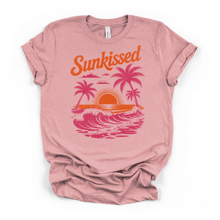 Heather pink t-shirt with a vintage-style Sunkissed beach graphic featuring palm trees rolling waves and an orange retro sunset on the front