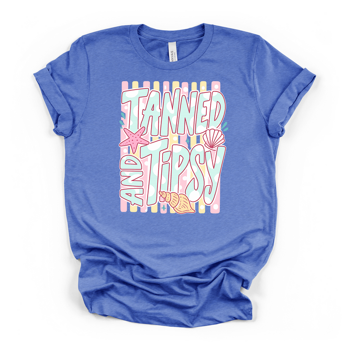 Heather columbia blue t-shirt with a fun pastel Tanned and Tipsy retro lettering graphic with shells and starfish on a striped background