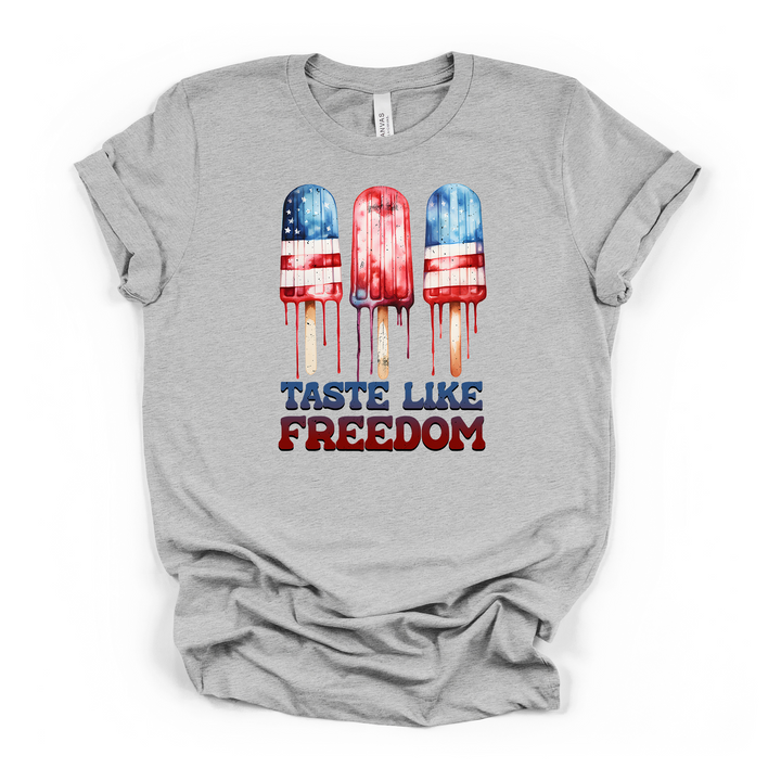 Athletic heather t-shirt with a watercolor graphic of three dripping American flag popsicles and Taste Like Freedom printed on the front