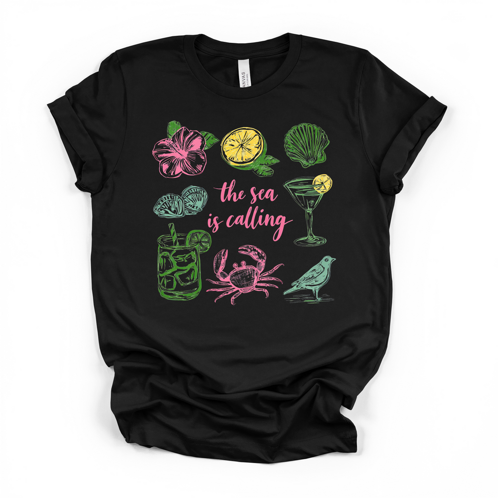 The Sea is Calling beach graphic t-shirt in black with colorful coastal icons including crab, seashell, hibiscus, and cocktails