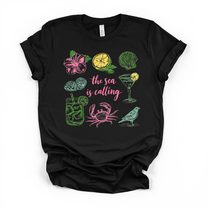 The Sea is Calling beach graphic t-shirt in black with colorful coastal icons including crab, seashell, hibiscus, and cocktails