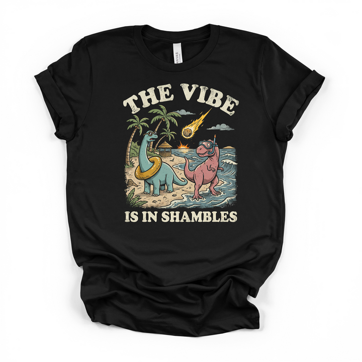 Black t-shirt featuring a retro dinosaur beach scene with a brontosaurus and T-rex and a meteor and The Vibe Is In Shambles text on the front