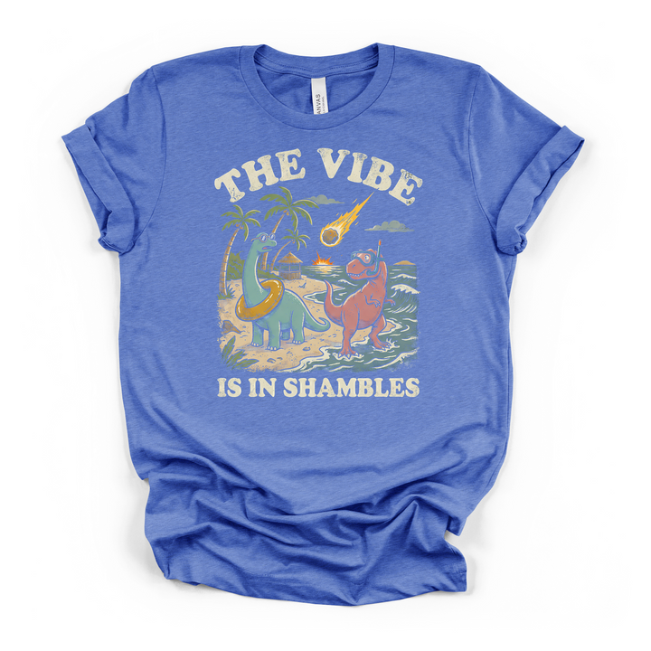 Heather columbia blue t-shirt with a retro dinosaur beach graphic showing two unbothered dinos and a meteor with The Vibe Is In Shambles text