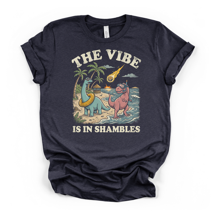 Heather navy t-shirt with a retro illustration of two dinosaurs on a beach with a meteor and The Vibe Is In Shambles text on the front