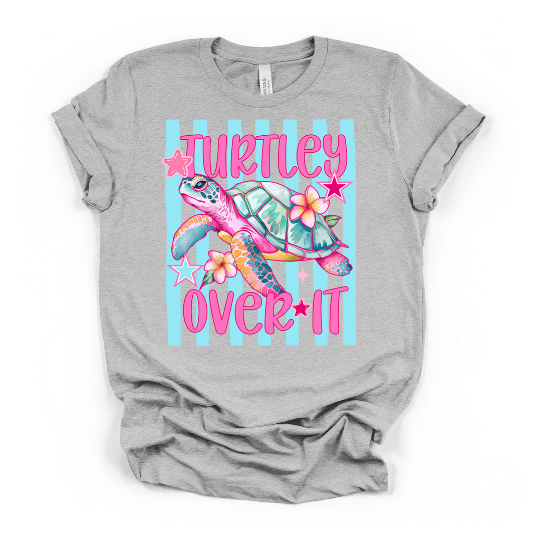 Athletic heather t-shirt with a bright colorful sea turtle surrounded by tropical flowers and stars on a blue striped background with Turtley Over It in hot pink