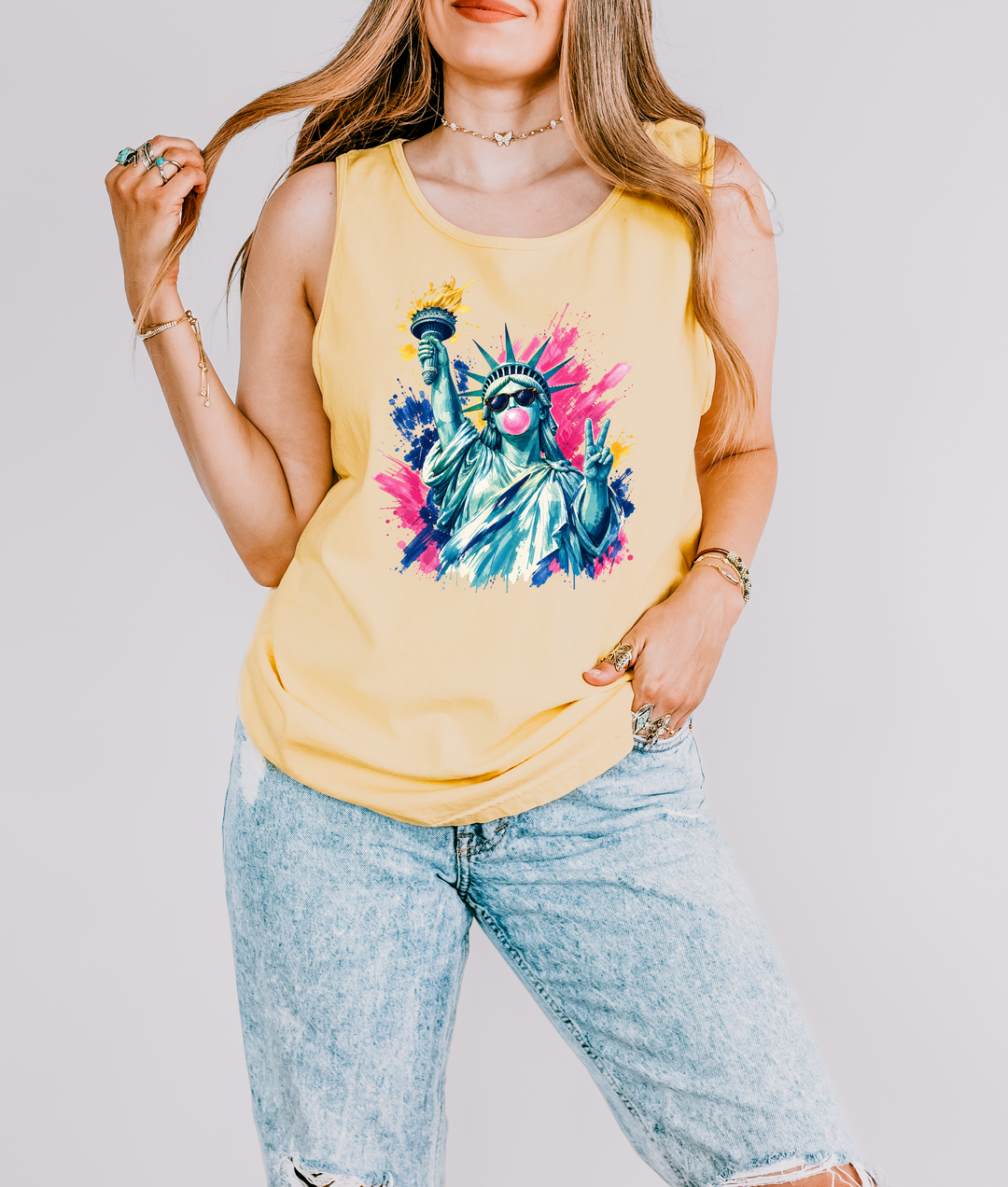 Bubblegum Liberty patriotic tank top in Butter yellow with a pop art Statue of Liberty wearing sunglasses blowing bubblegum and flashing a peace sign