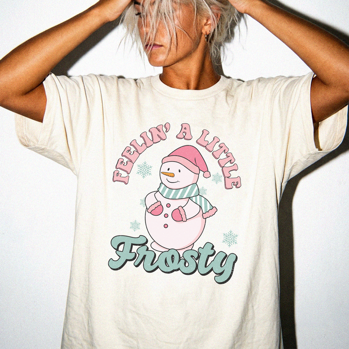 Feelin a Little Frosty snowman Christmas shirt in Ivory with retro pink arched text, a cute snowman, and teal Frosty lettering