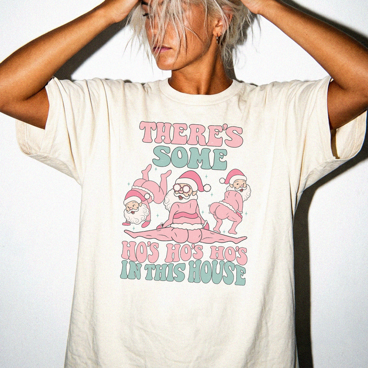 Theres Some Ho Ho Hos in This House funny Christmas shirt in Ivory with three dancing retro Santas and pink and teal retro text