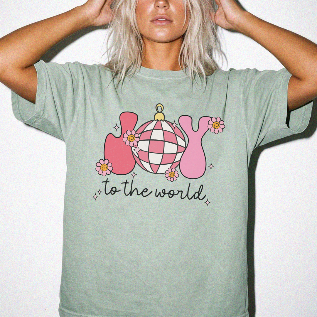 Joy to the World Christmas shirt in Bay green with retro pink JOY letters, a checkered ornament, and daisy accents